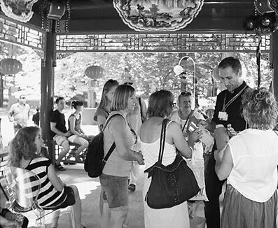 當地導游正在向游客展示中國亭榭的建筑材料模型。